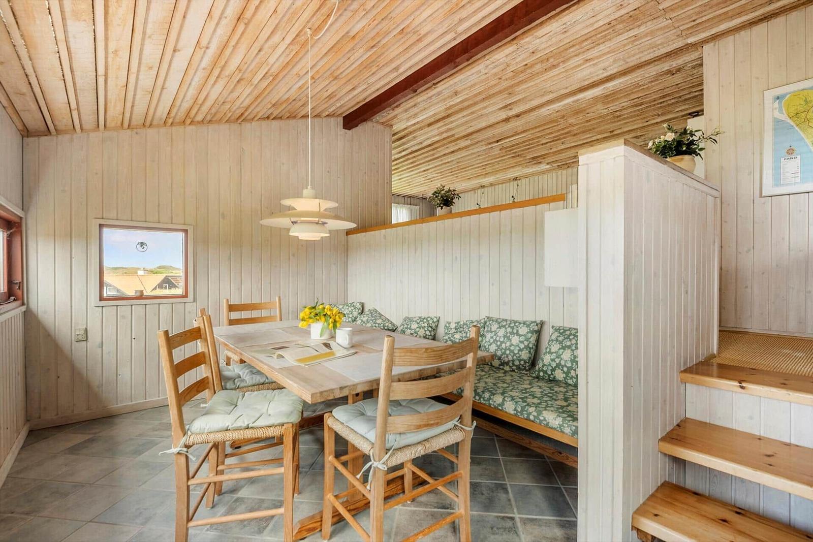 Esszimmer mit Holztisch, Stühlen und Sitzbank. Holzwände und -decke. Fenster mit Blick.