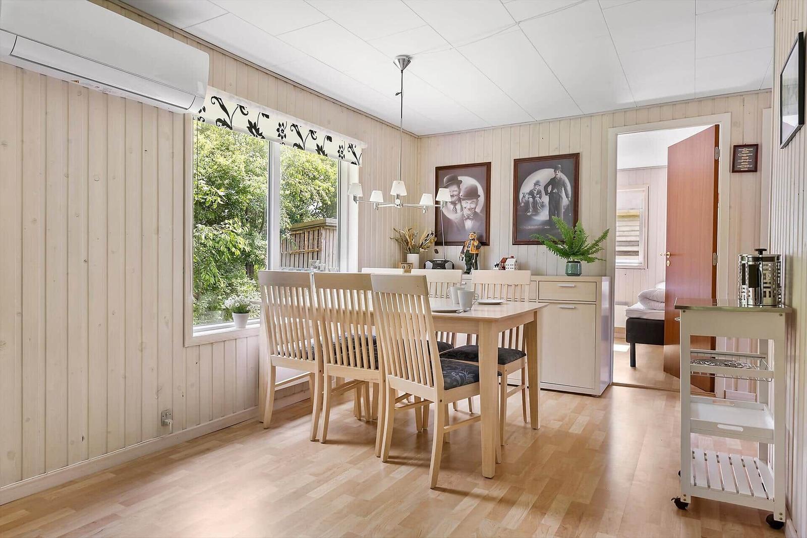 Dining room with wooden table, chairs, and view of greenery