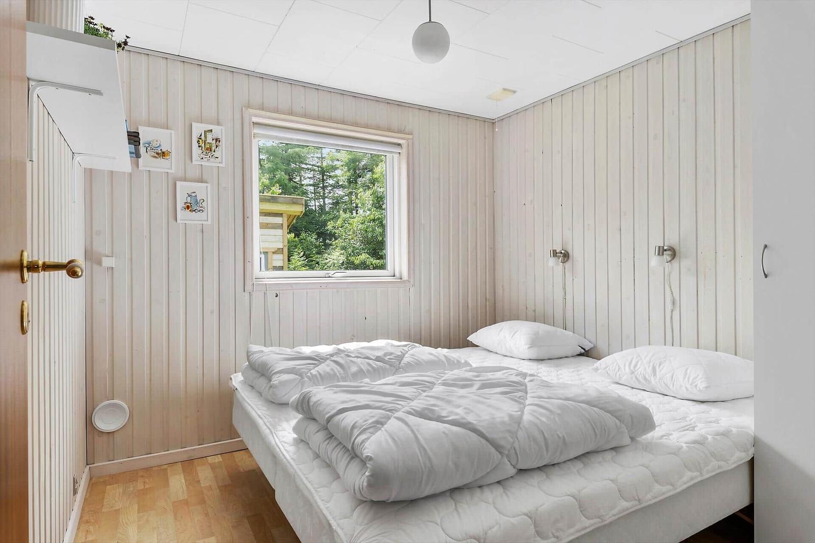 Bedroom with bed, window, and wood paneling.