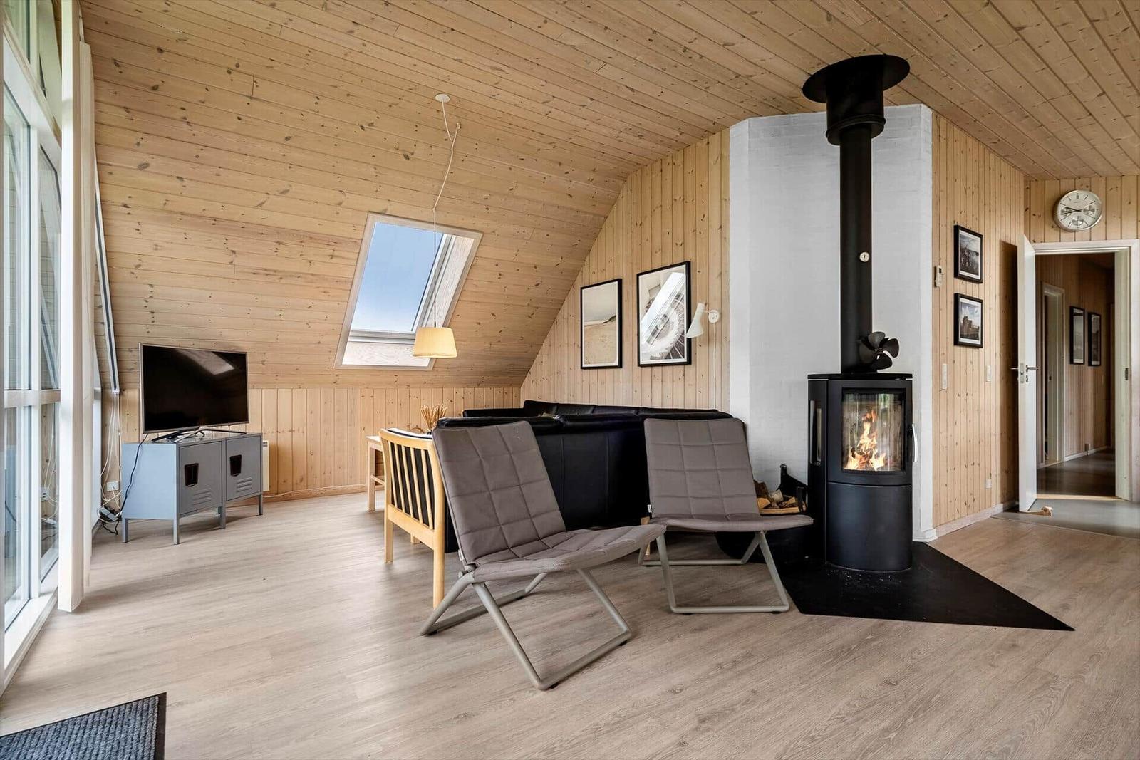Wohnzimmer mit Holzdecke, Kamin und Fernseher