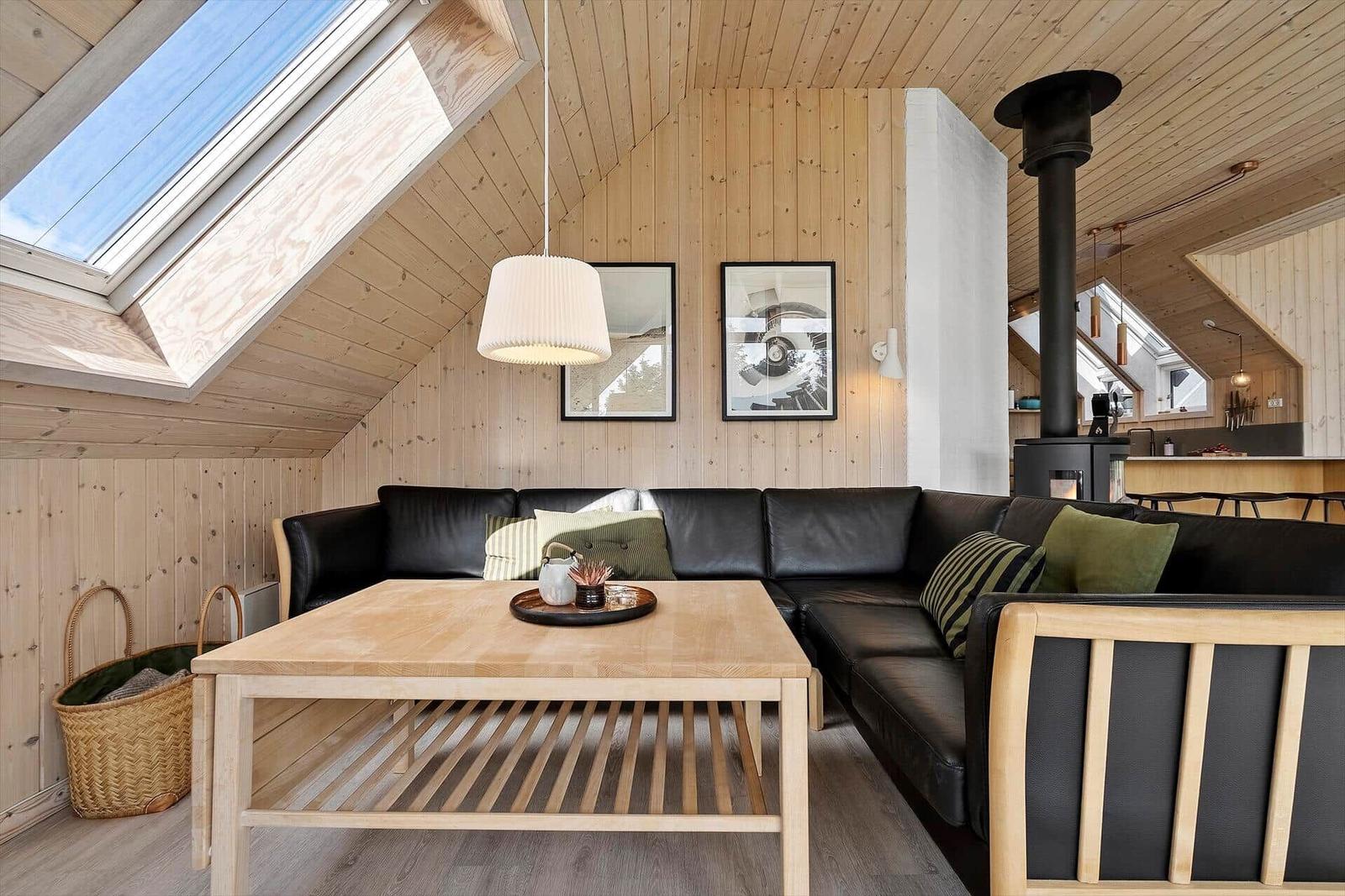 Wohnbereich mit Holzwand, Sofa, Tisch und Dachfenster
