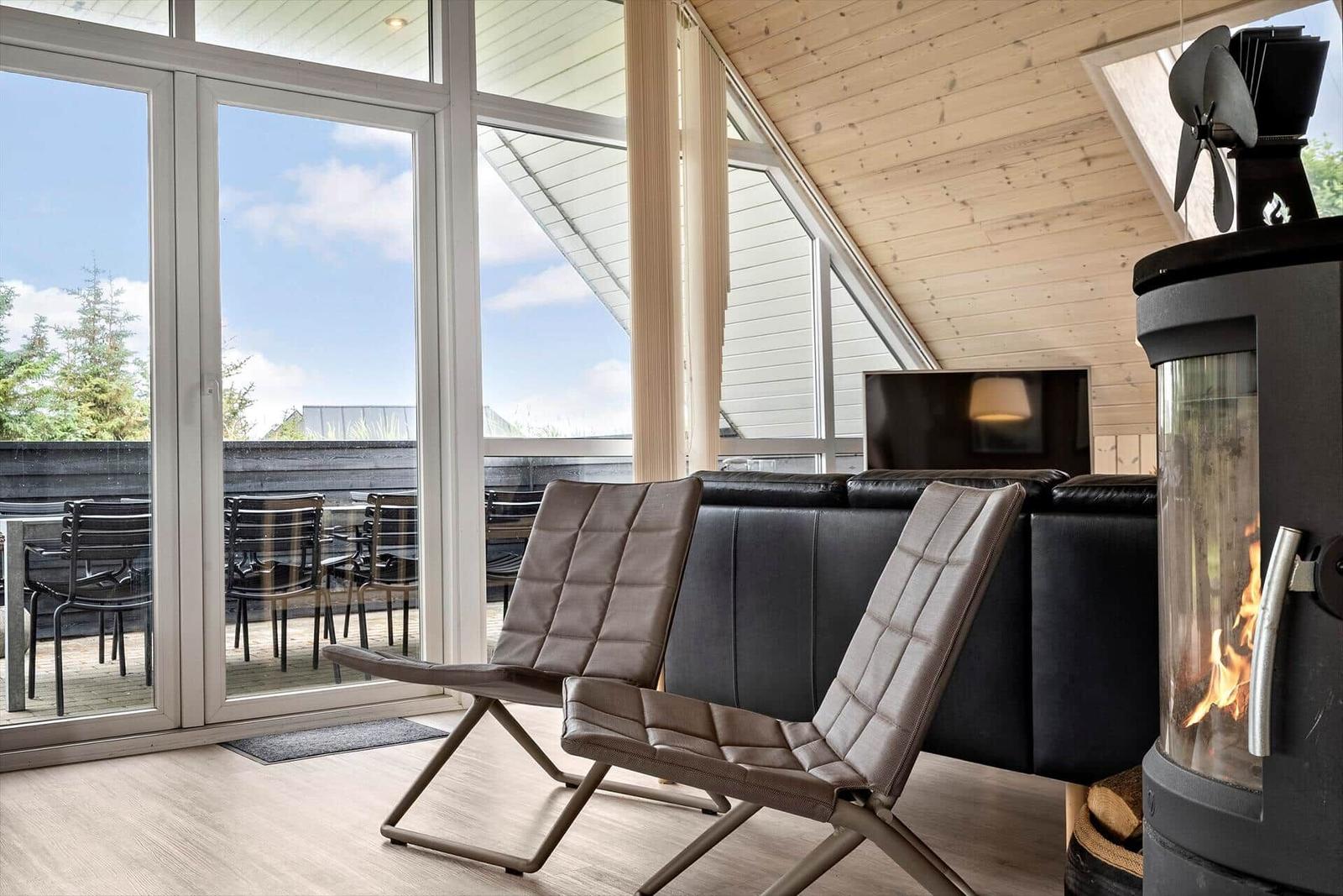 Loungebereich mit Sitzgelegenheiten und Kamin. Durchgang zur Terrasse mit Gartenmöbeln.