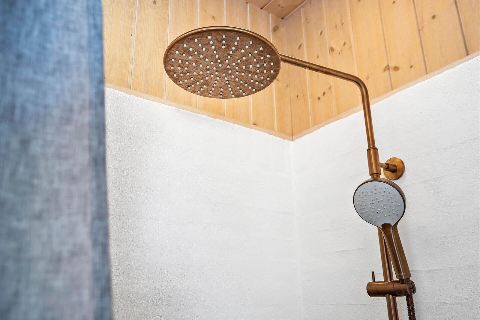 Dusche mit kupferfarbenem Duschsystem und Holzdecke