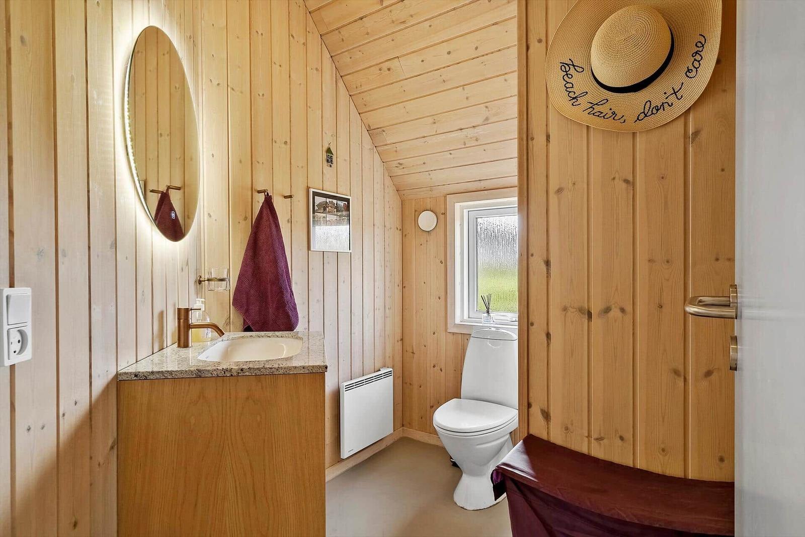 Holzbadezimmer mit Waschbecken, Toilette und Fenster.