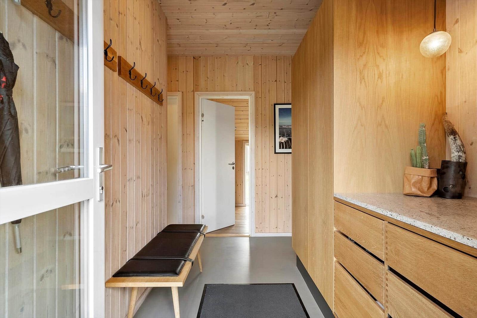 Hallenbereich mit Holzwand, Bank, Garderobe und Schrank