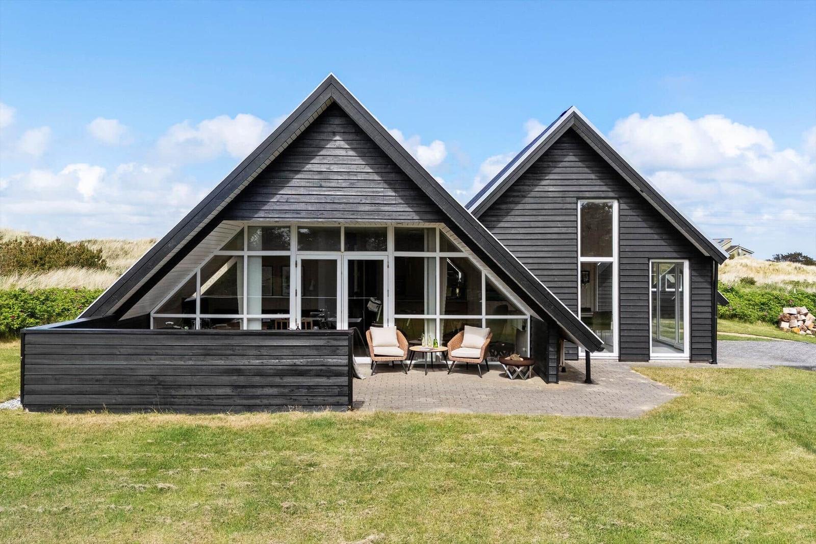 Moderne Holzhütte mit großem Glasbereich und Außenterrasse.