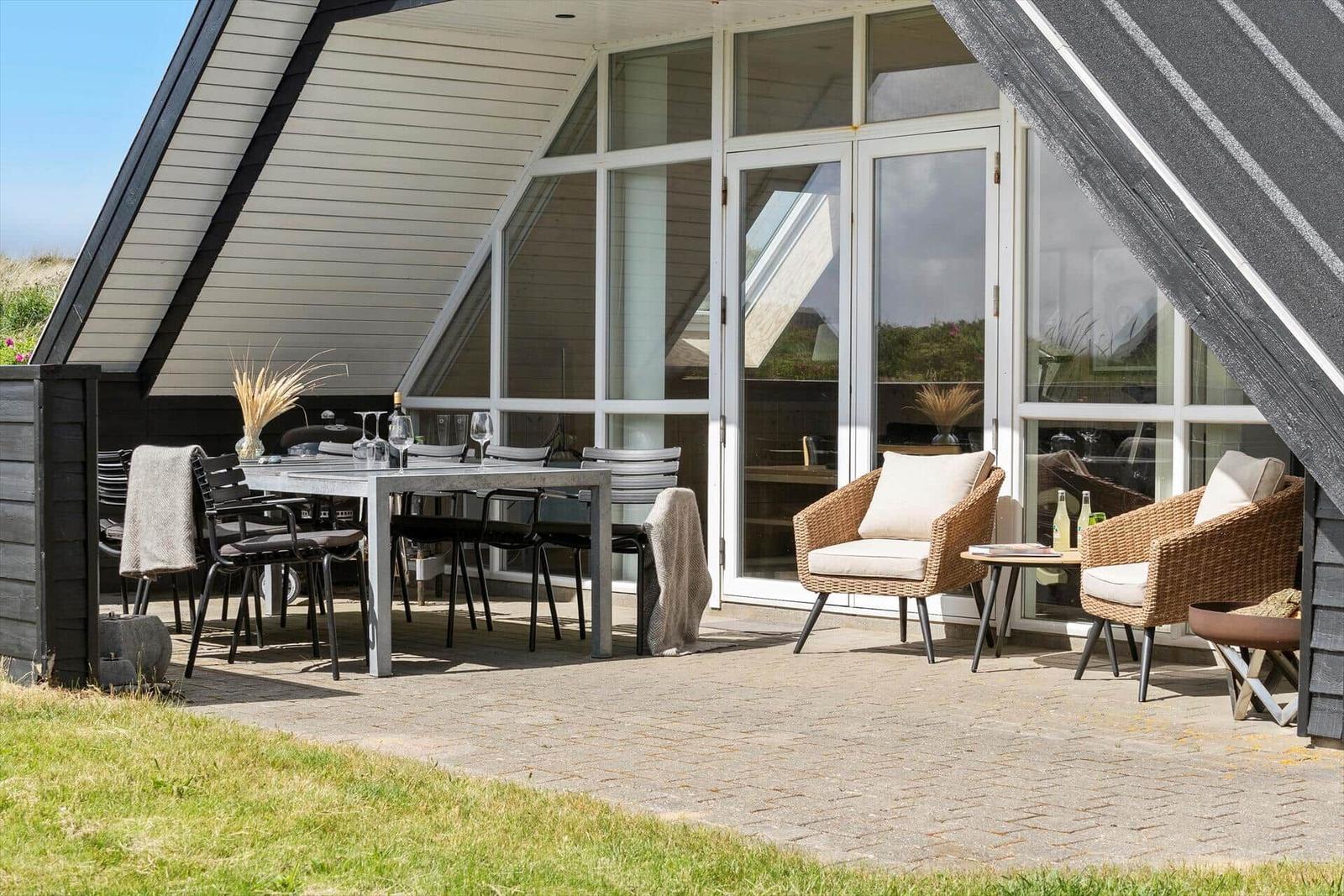 Terrasse mit Esstisch, Stühlen und zwei Sesseln unter Dach