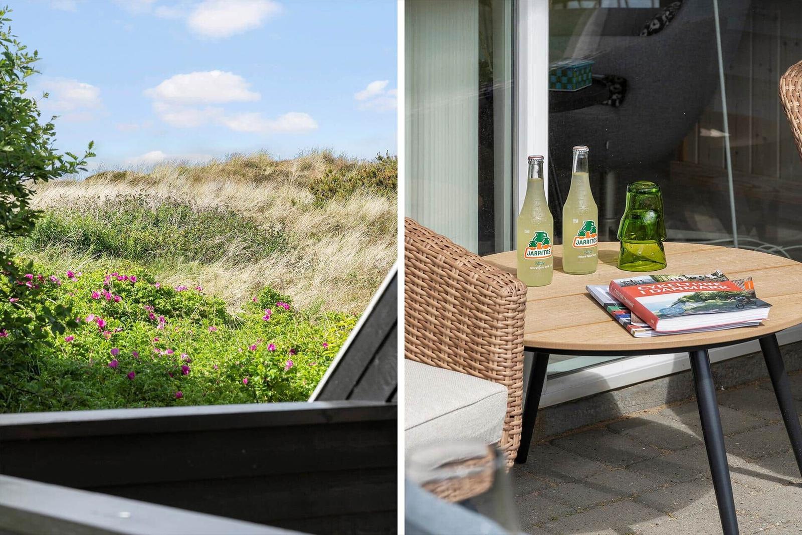 Terrasse mit Tisch, Stühlen und Blick auf Dünen.