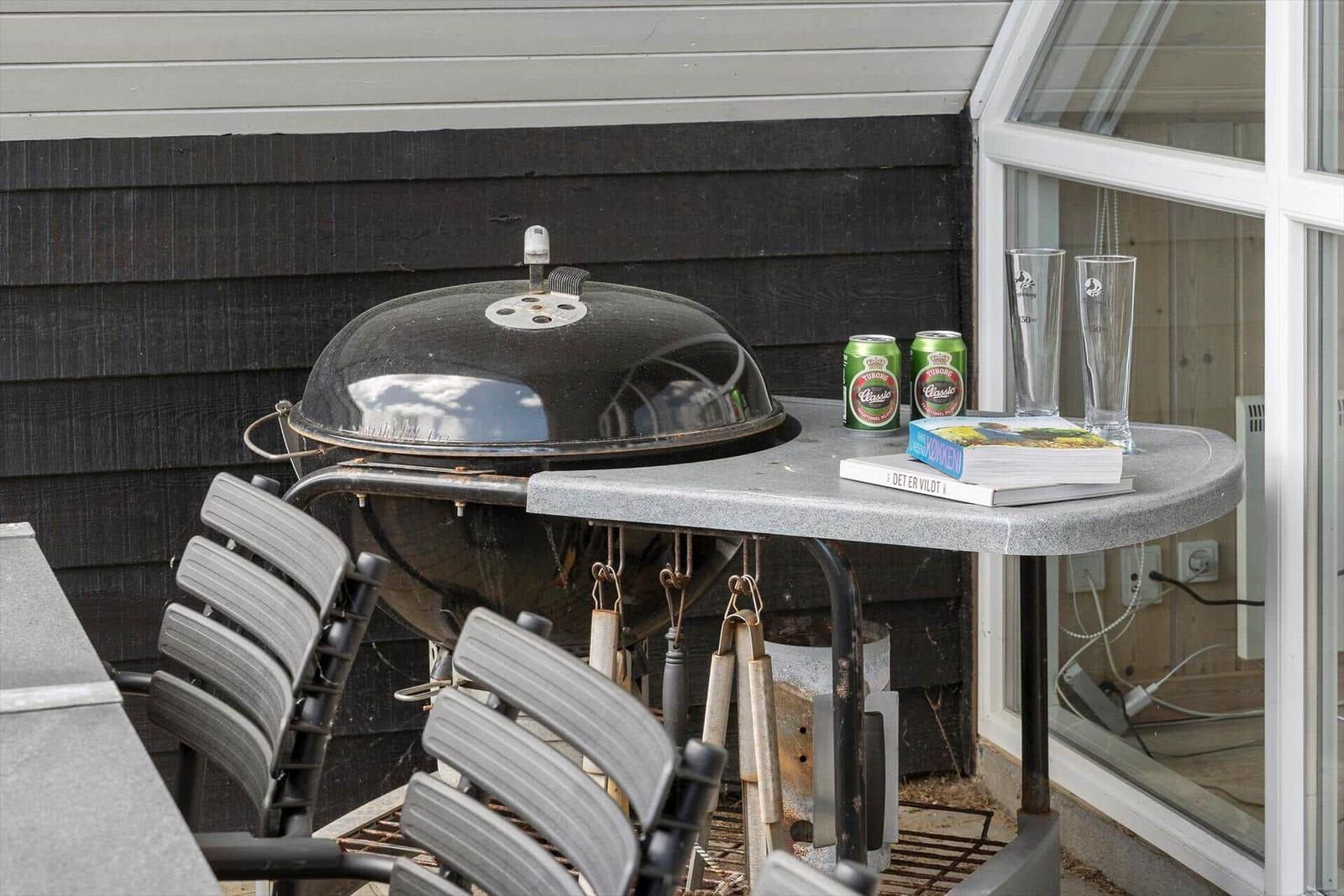 Außenbereich mit Grill, Tisch, Stühlen und Getränken.