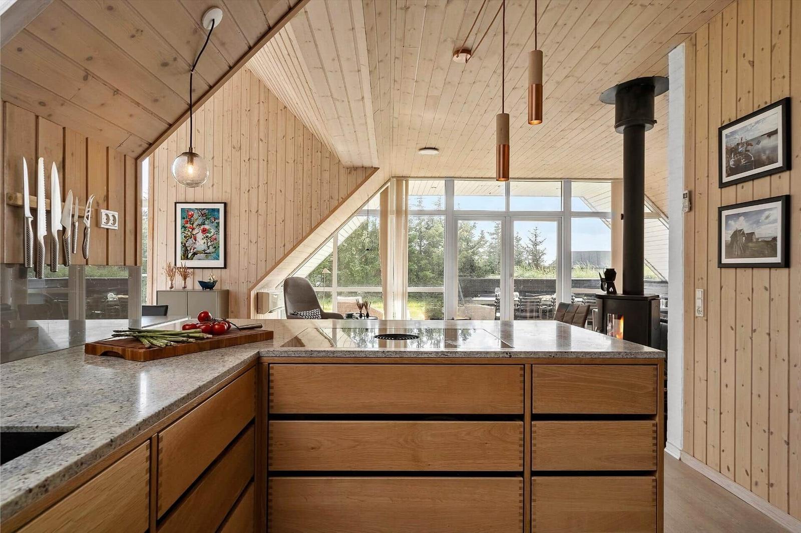 Küche mit Holzwand, Arbeitsplatte und Fenster zum Garten.