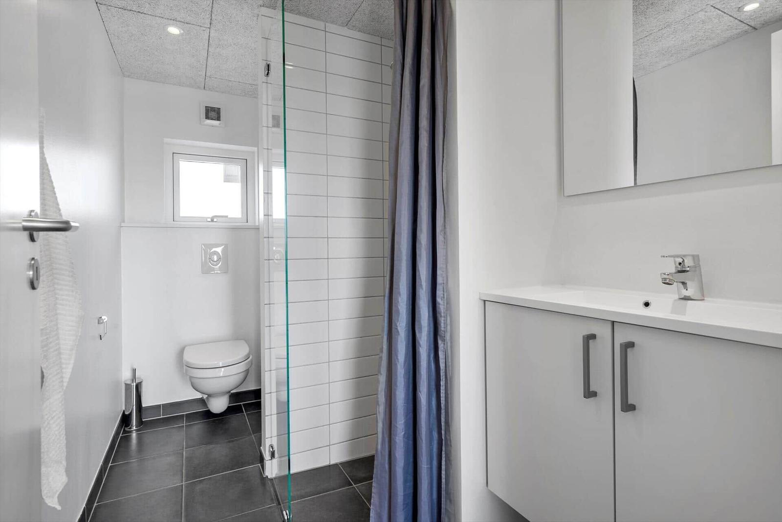 Badezimmer mit Dusche, Waschbecken und Toilette.