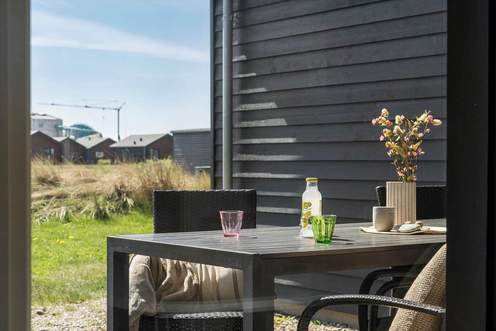 Terrasse mit Tisch, Stühlen und Blick auf Grasland und Häuser.