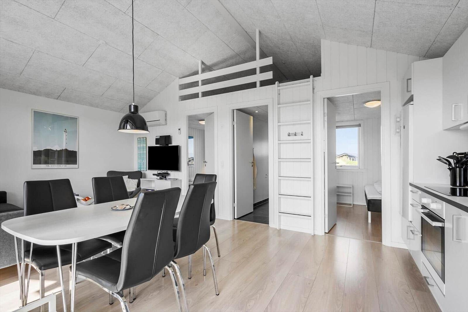Wohnung mit Essbereich, Schlafbereich und Küche. Weiße Wände und Holzboden.