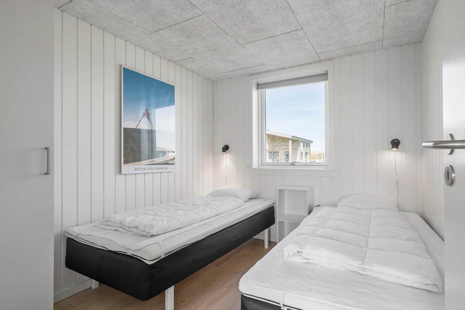 Zimmer mit zwei Betten, Fenster und Wandbild.