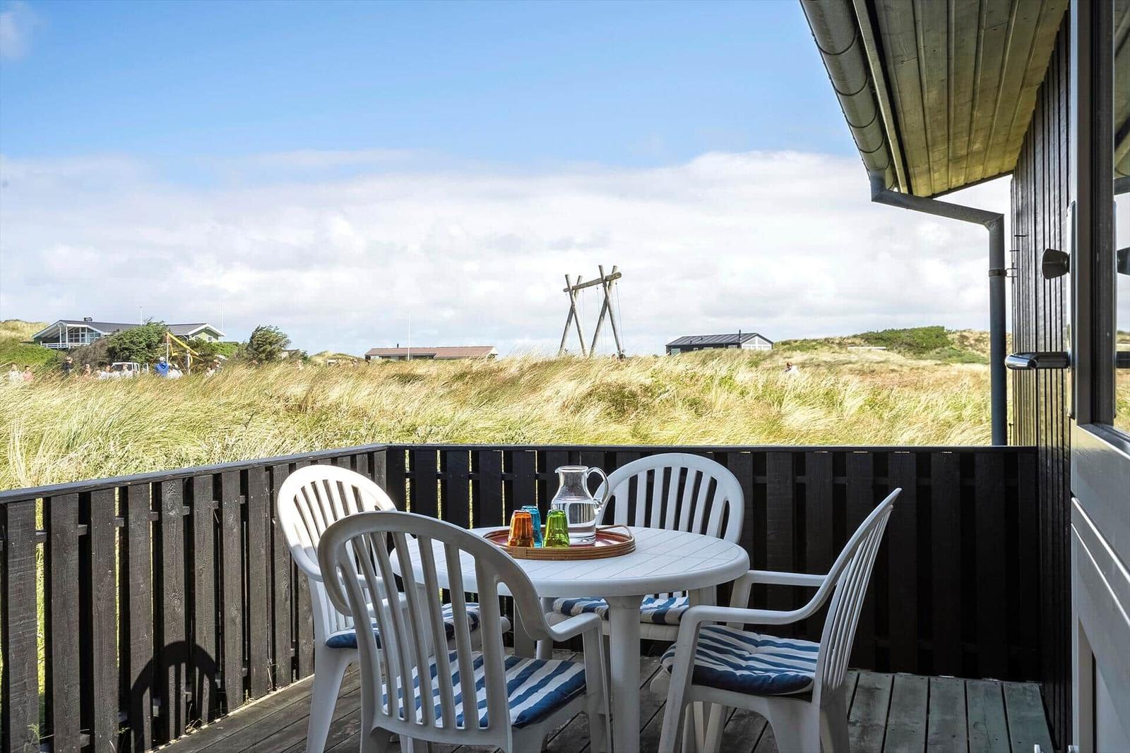 Terrasse mit Tisch und Stühlen, Blick auf Grasland und Häuser
