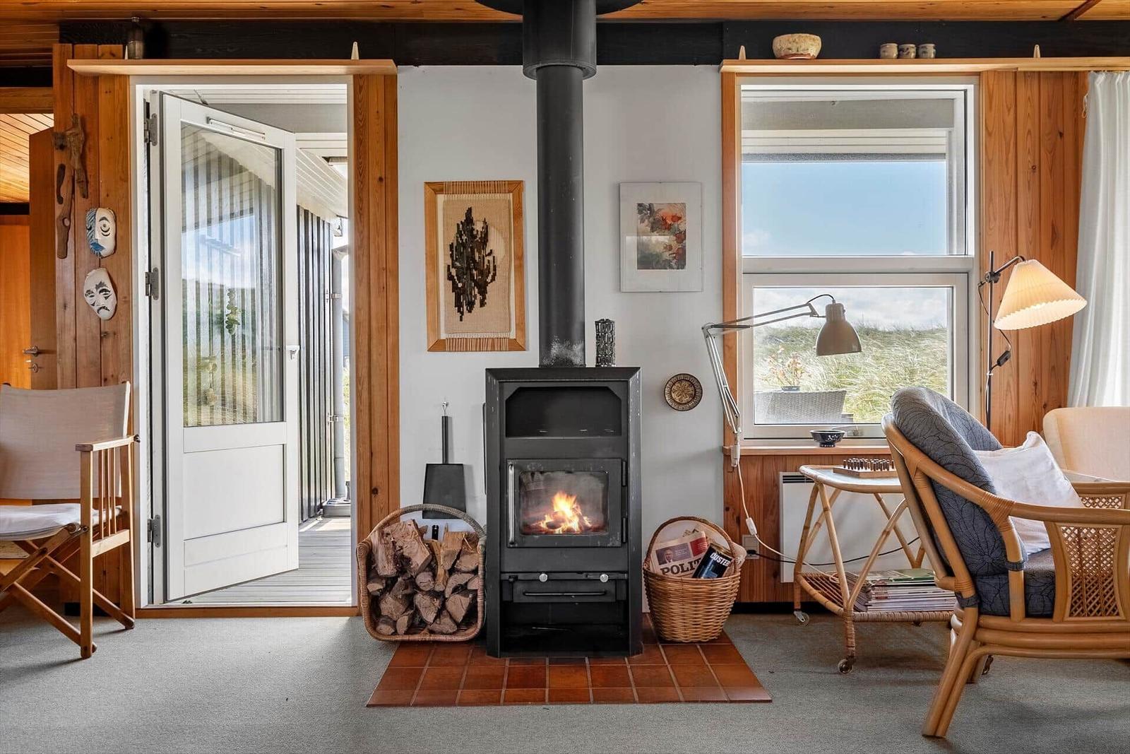 Ein Wohnzimmer mit Kamin, Sitzgelegenheiten und Blick auf die Landschaft.