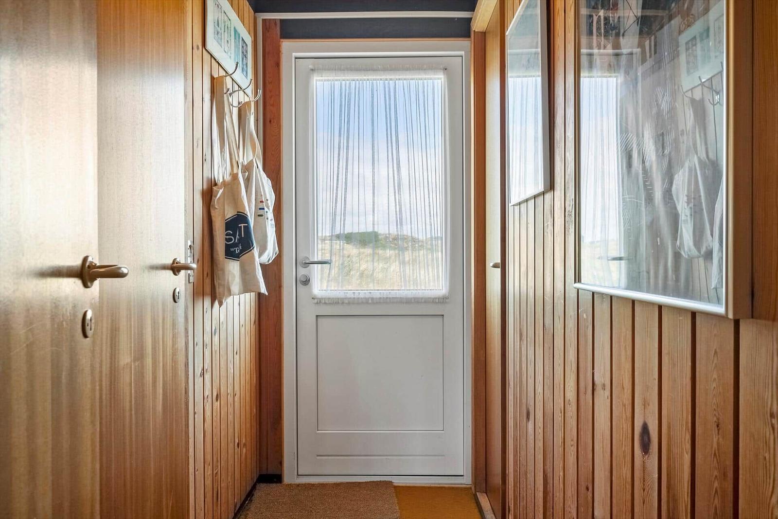 Hausgang mit Holzwand und Tür zum Strand.