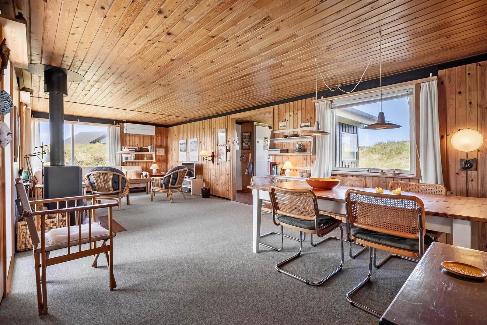Großes Wohn- und Esszimmer mit Holzdecke, Esstisch und Sitzgelegenheiten.
