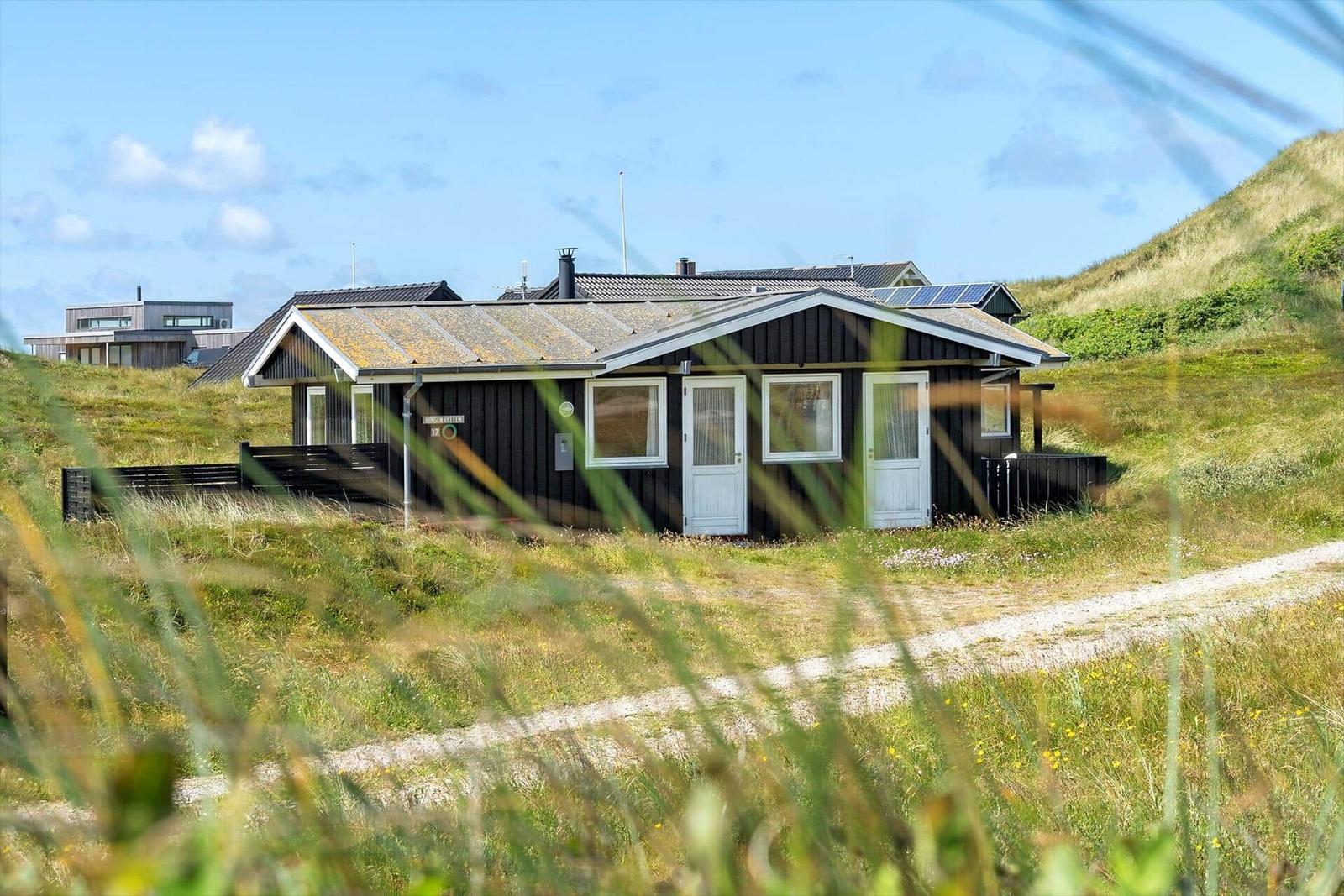 Holzhaus mit weißen Türen und Fenstern auf grüner Wiese
