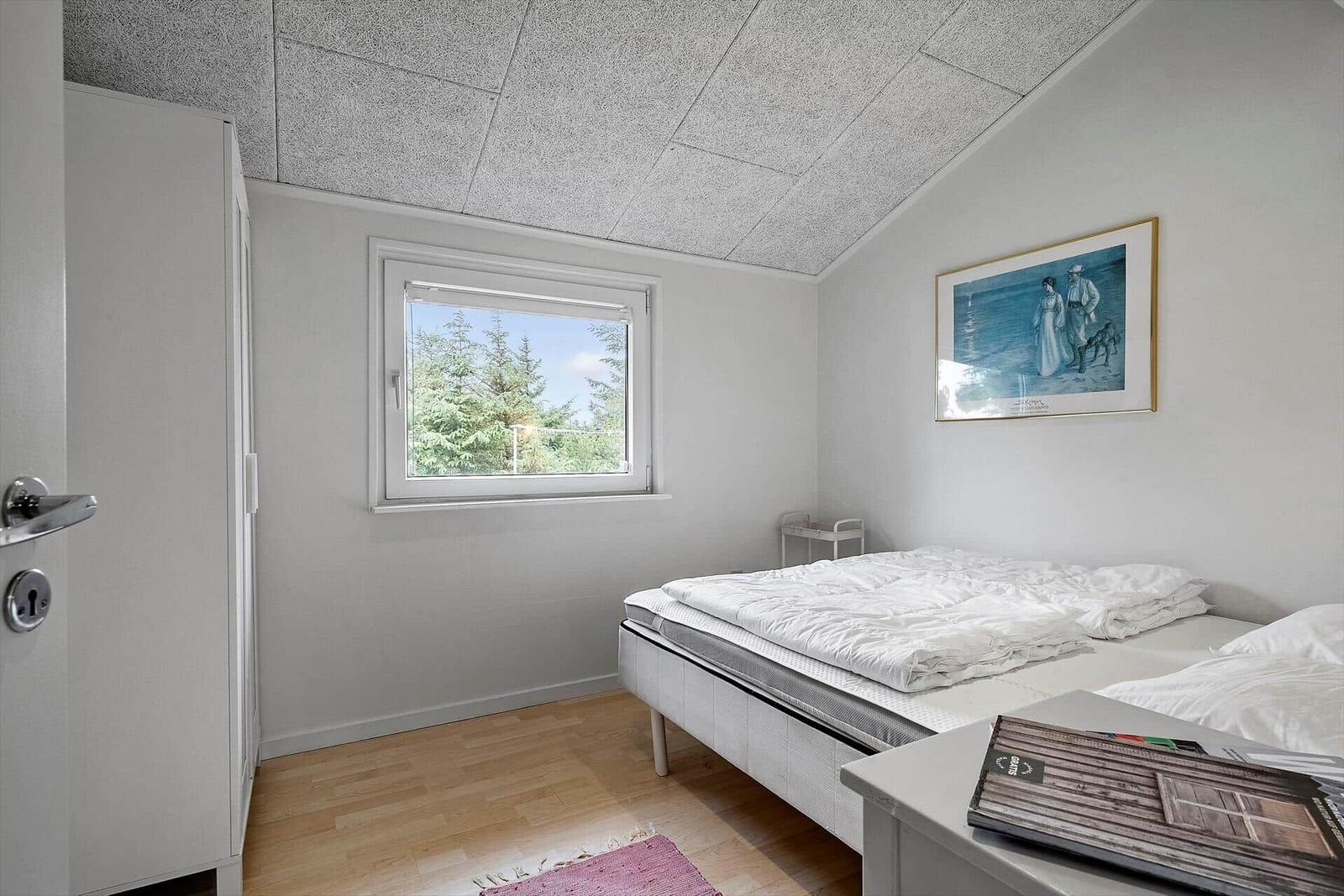 Schlafzimmer mit Bett, Fenster und Kleiderschrank.