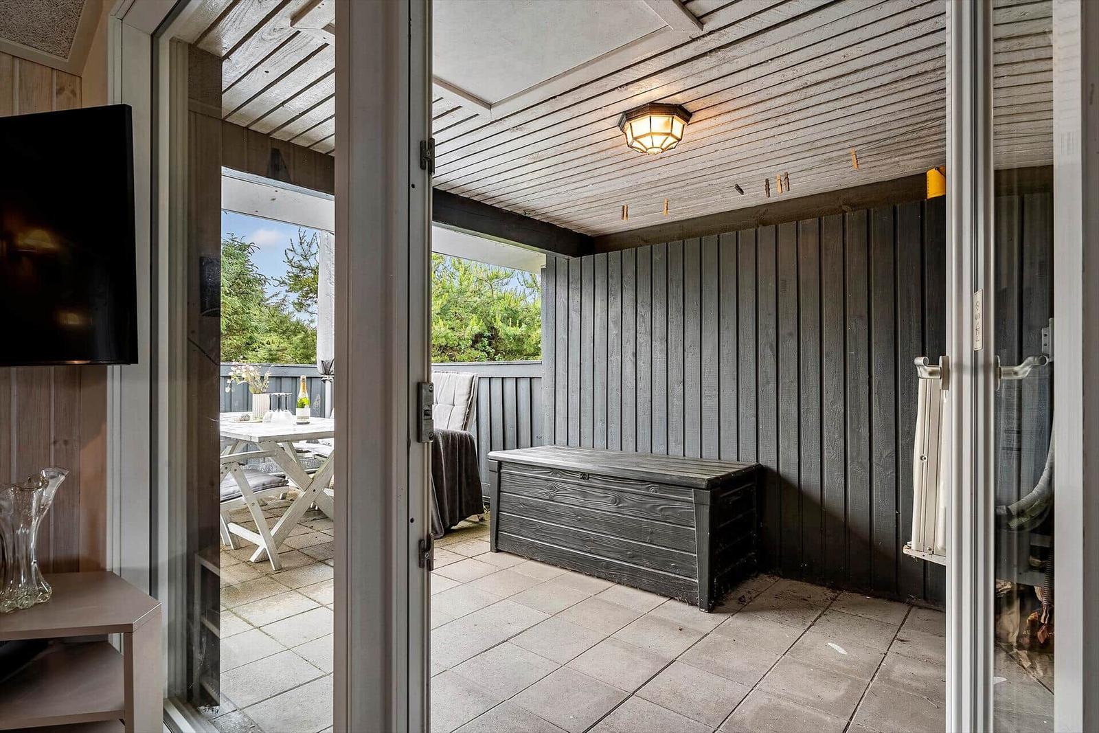 Terrasse mit Tisch, Bank und Grillmöglichkeit. Holzwände und Dach.