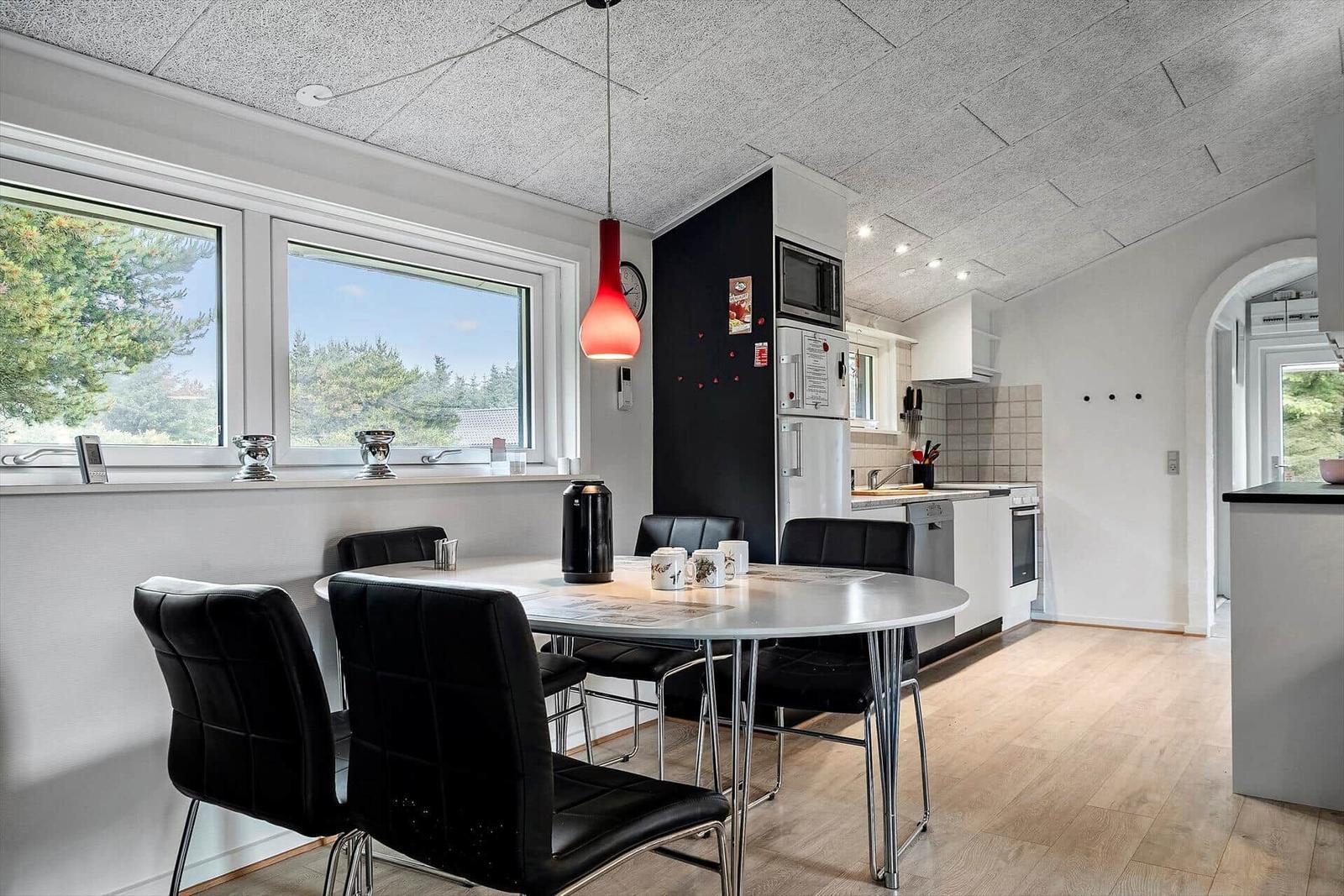 Essbereich mit Tisch und Stühlen, Küche mit Küchenschränken und Fensterblick.