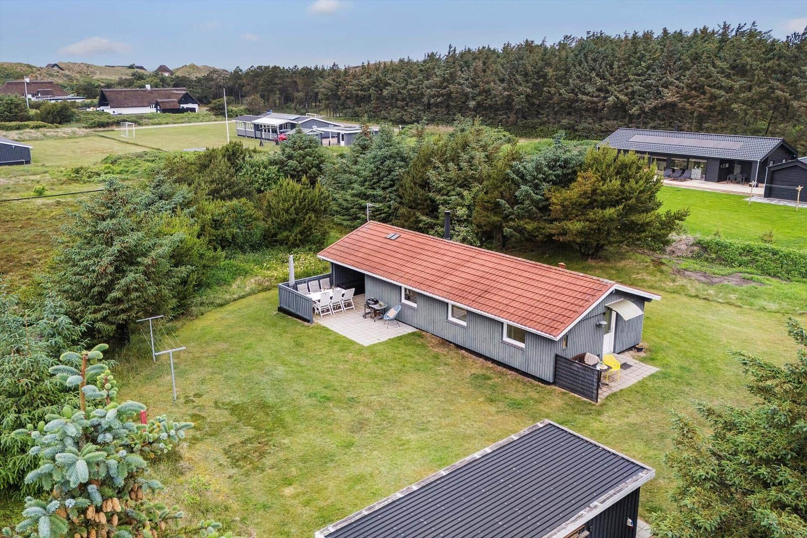 Ein Haus mit rotem Dach und Terrasse im Grünen.