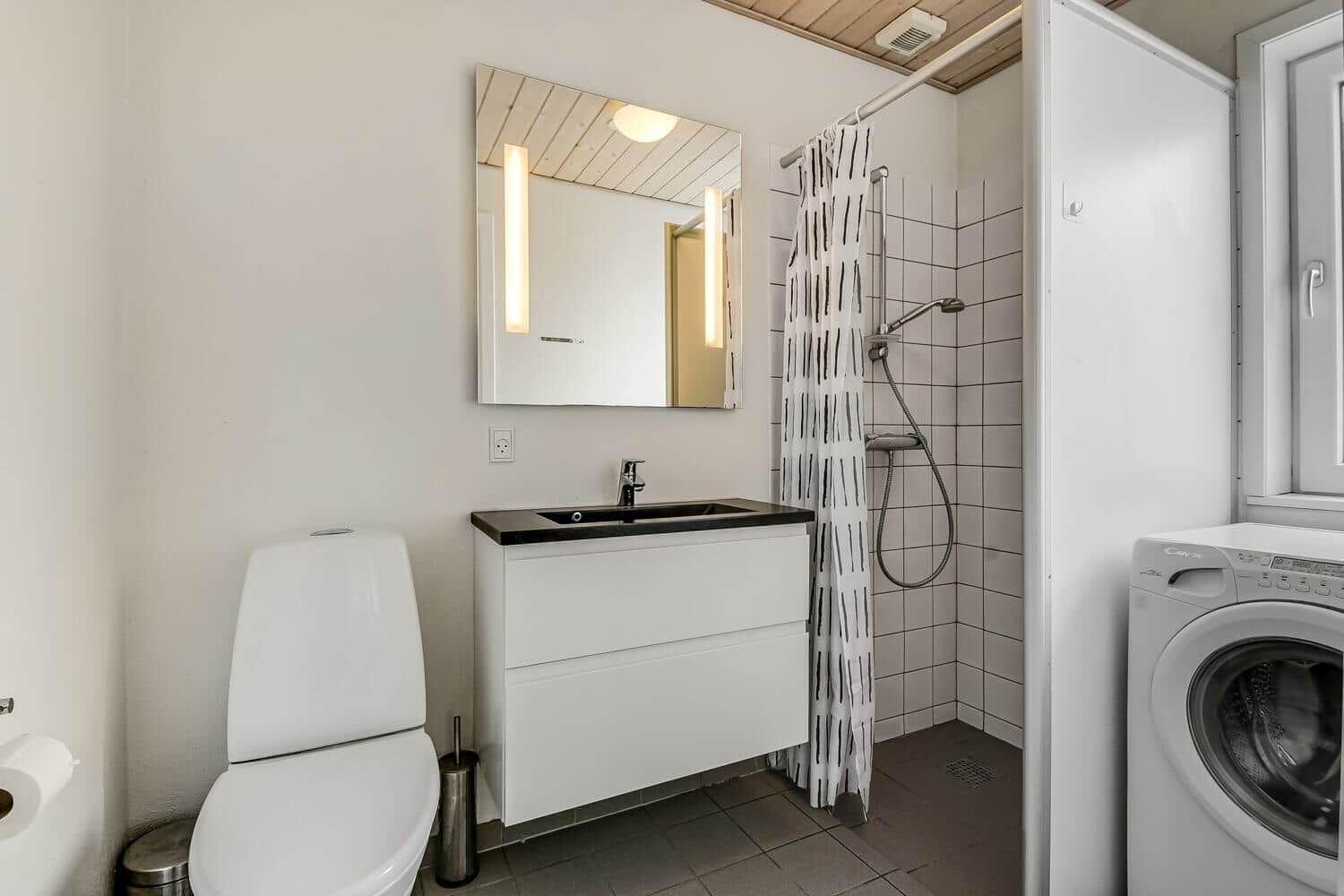 Badezimmer mit Dusche, Waschbecken und Waschmaschine