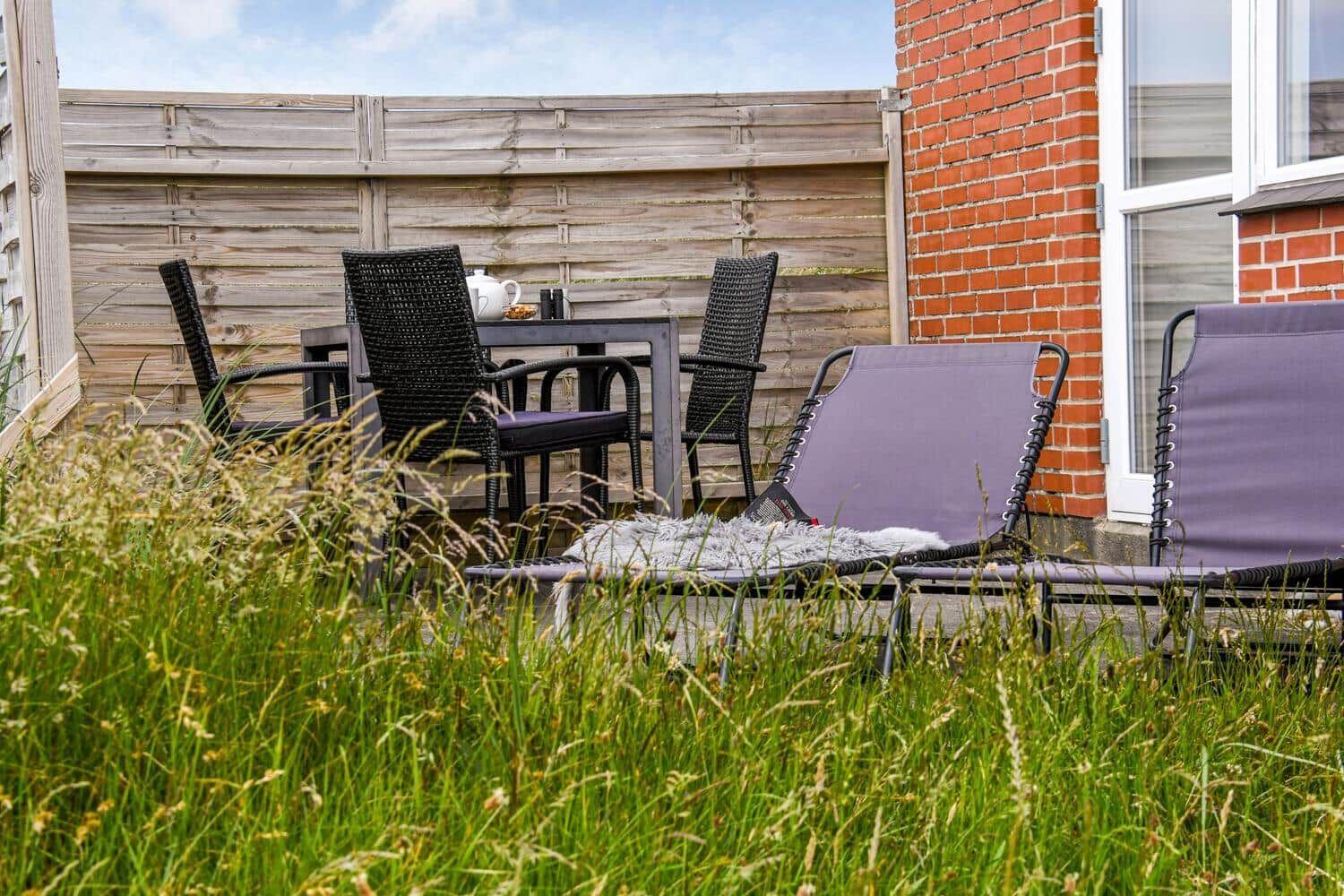 Terrasse mit Tisch, Stühlen und Liegestühlen neben Backsteinhaus