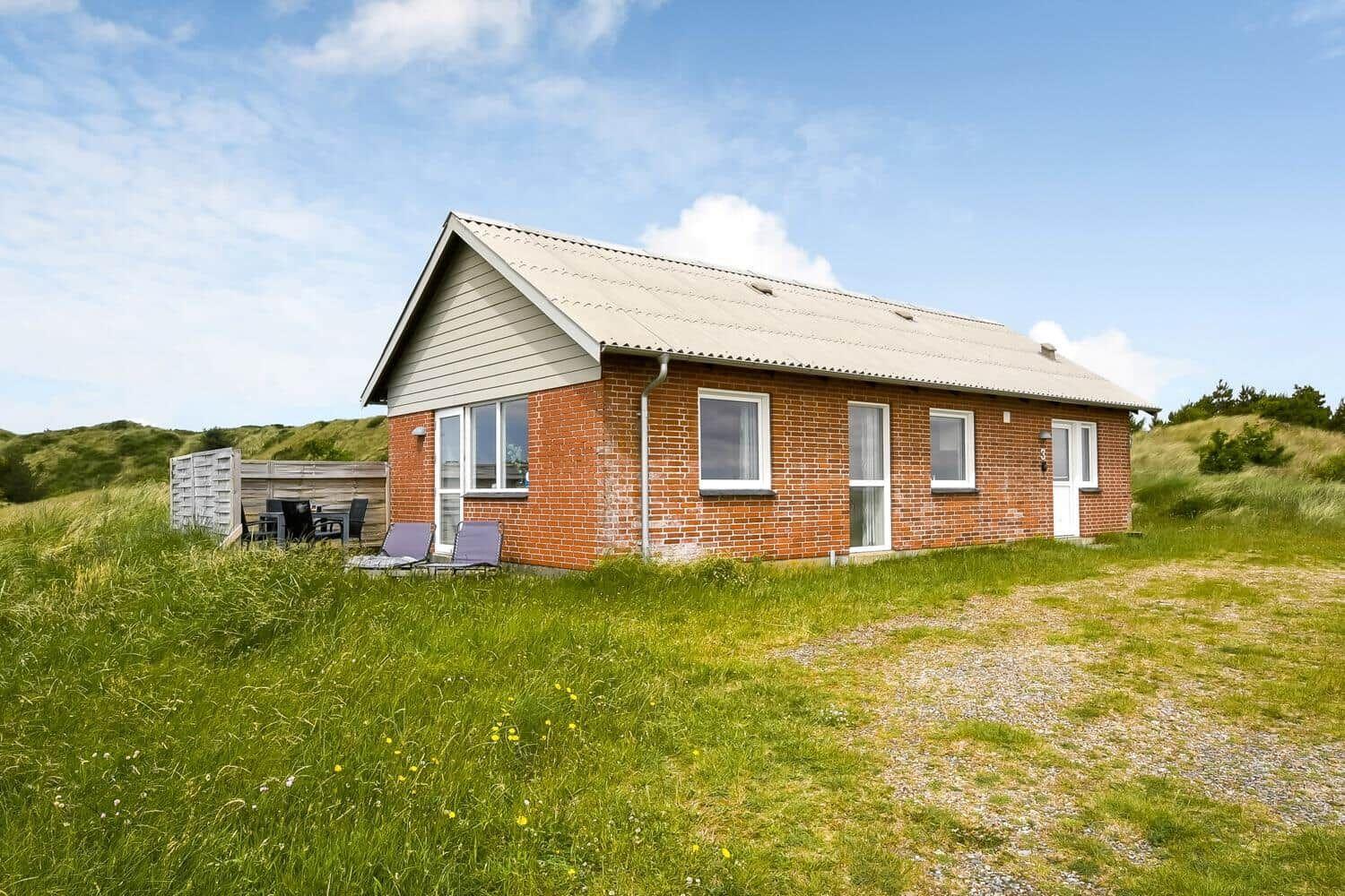 Ein kleines Haus mit Backsteinfassade und Terrasse im Grasland.