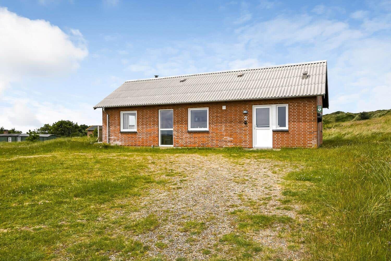 Ein kleines Haus aus roten Ziegeln mit grauem Dach und weißer Tür.