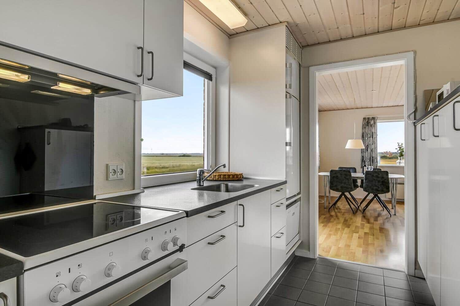 Küche mit Blick auf Feld, angrenzender Essbereich mit Tisch und Stühlen.