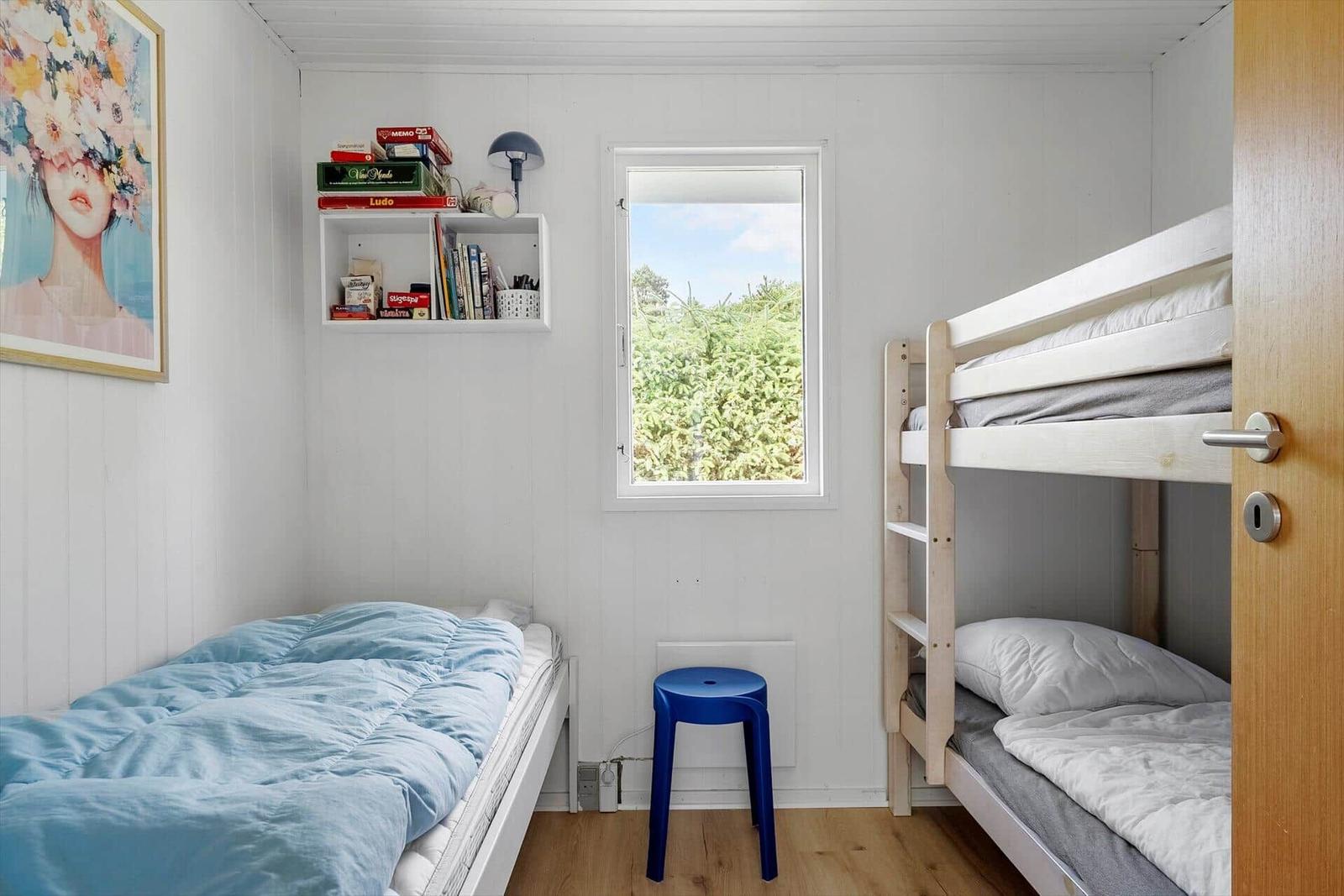 Zimmer mit Doppelbett, Einzelbett und Fenster mit Blick auf Grün.
