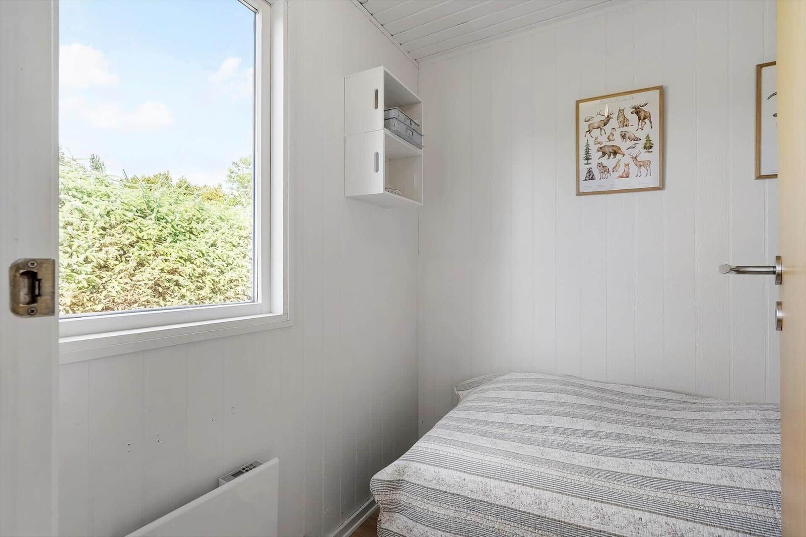 Schlafzimmer mit Bett, Fenster und Wandbild.