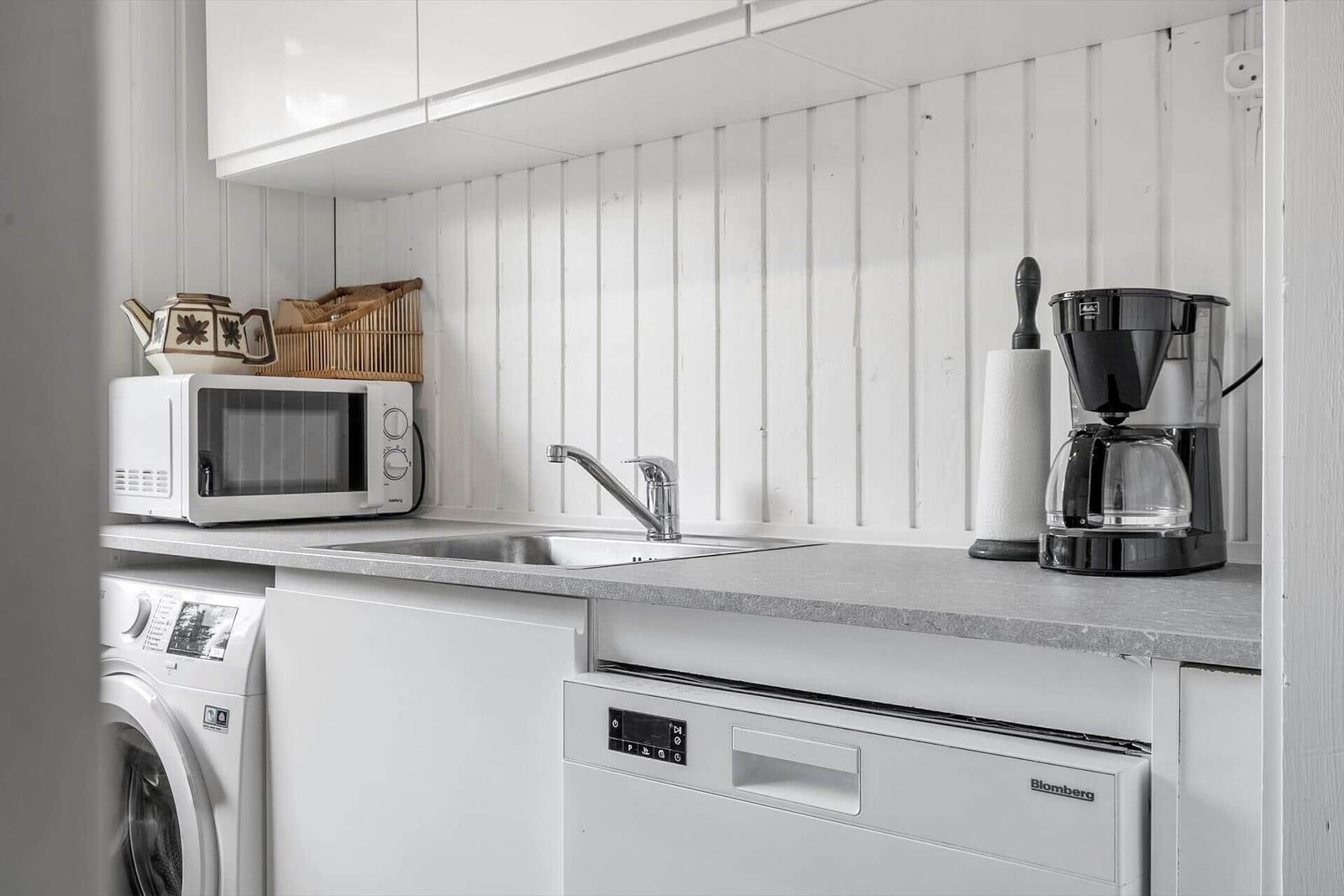 Küche mit Spüle, Mikrowelle, Kaffeemaschine und Waschmaschine.