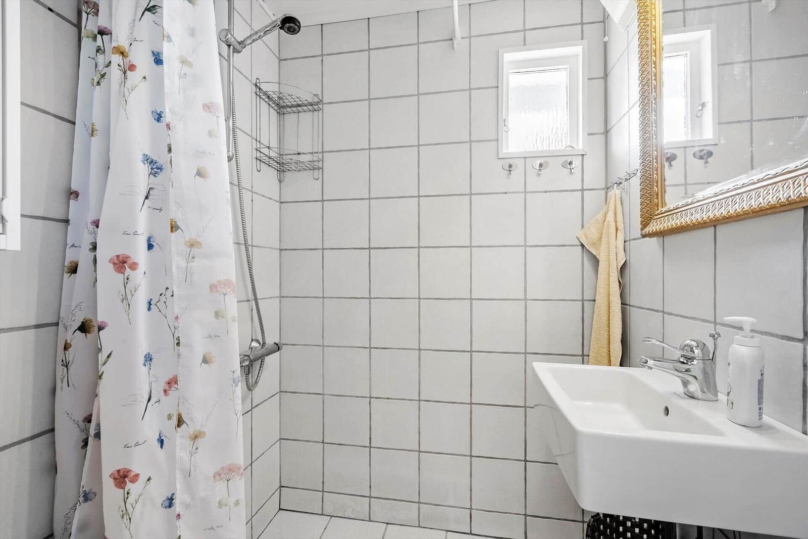 Badezimmer mit Dusche, Waschbecken und Spiegel