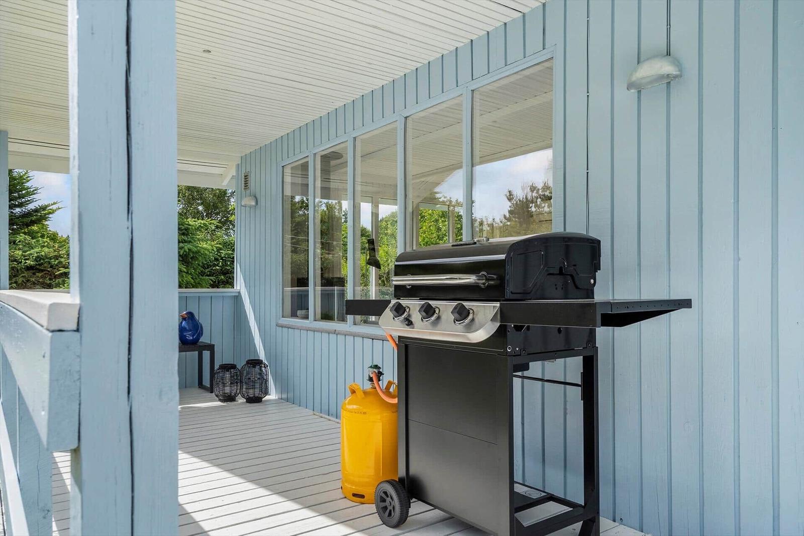 Gaszugang auf Terrasse mit Grill und gelber Gasflasche.