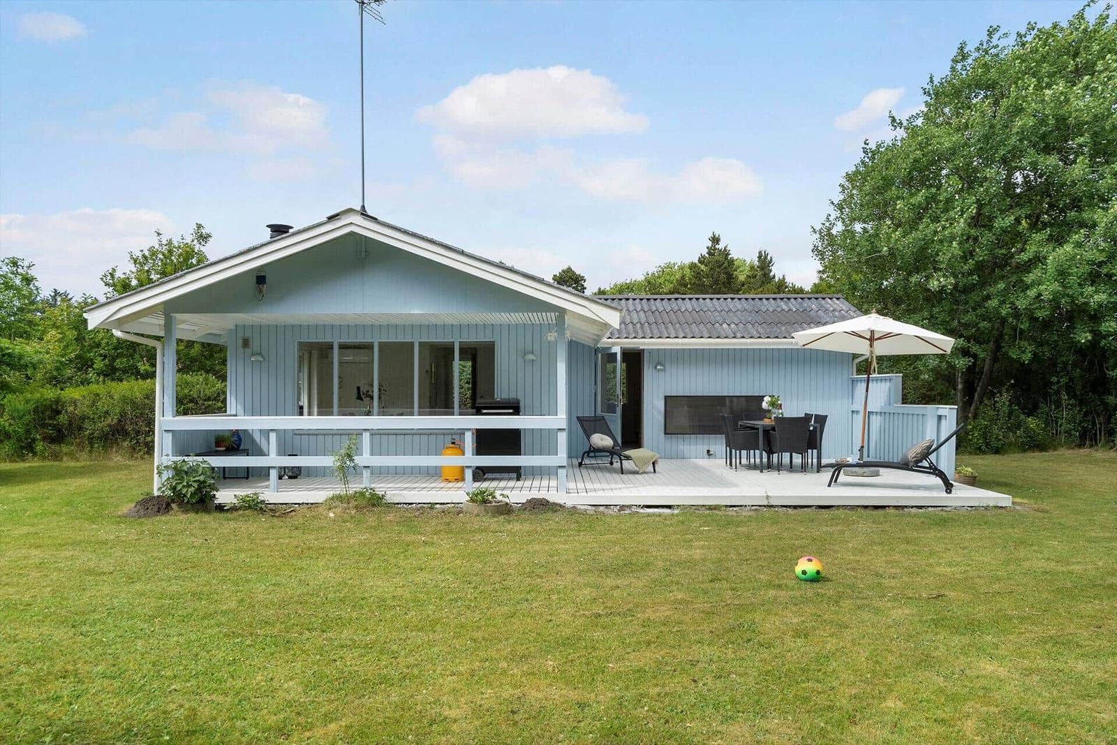 Blau gestrichenes Haus mit Terrasse, Garten und Grillplatz.