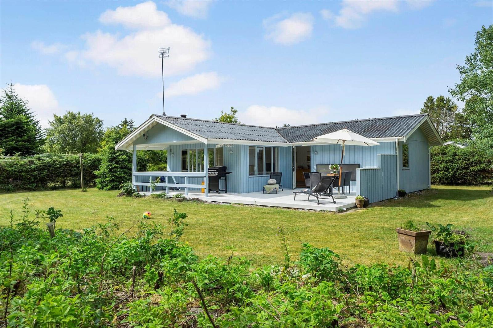 Blauer Gartenhaus mit Terrasse, Grill und Sitzgelegenheiten.