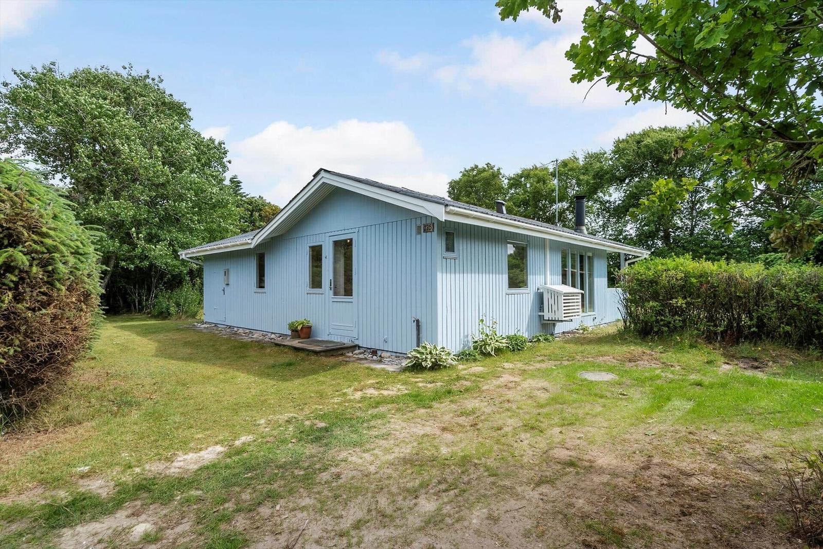 Ein hellblauer Holzhaus mit Garten und Bäumen umgeben.