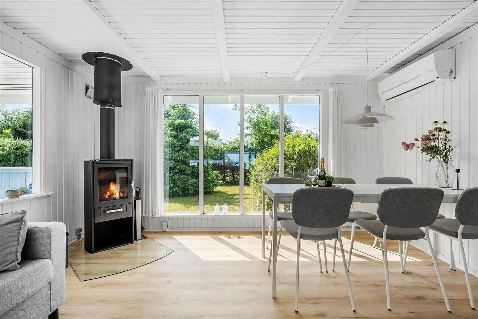 Moderne Küche mit Esstisch, Kamin und großem Fensterblick auf Garten.