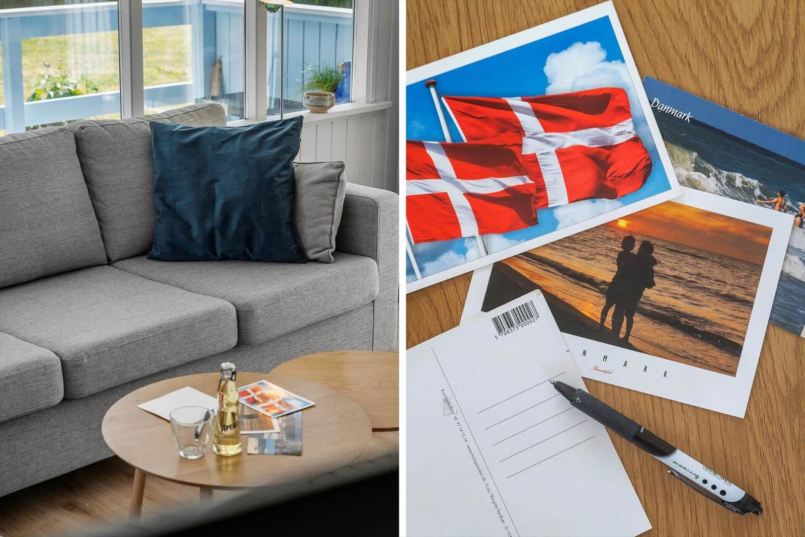Ein Wohnzimmer mit Sofa und Tisch. Daneben liegen Postkarten mit dänischen Motiven.