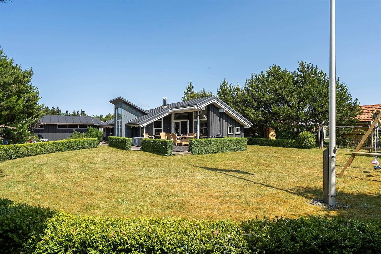 Moderne Villa mit Terrasse, Garten und Spielplatz. Umgeben von Bäumen und Rasen.