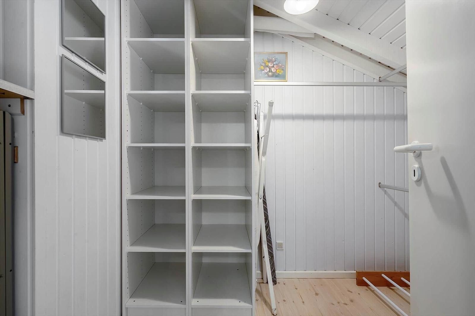 Große Garderobe mit Regalen und Kleiderständer unter Dachschrägen.
