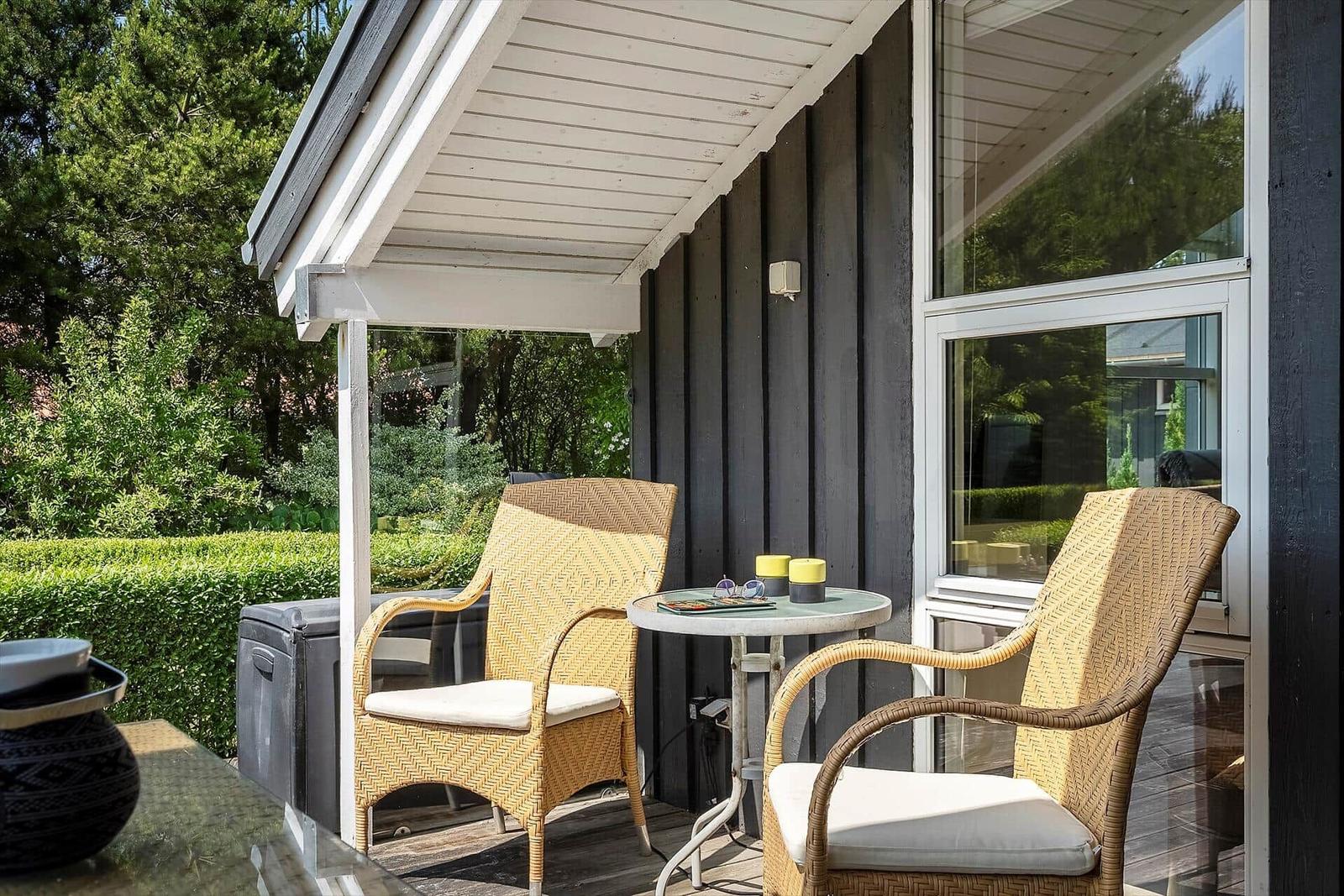 Terrasse mit zwei Stühlen und Tisch unter Dach.