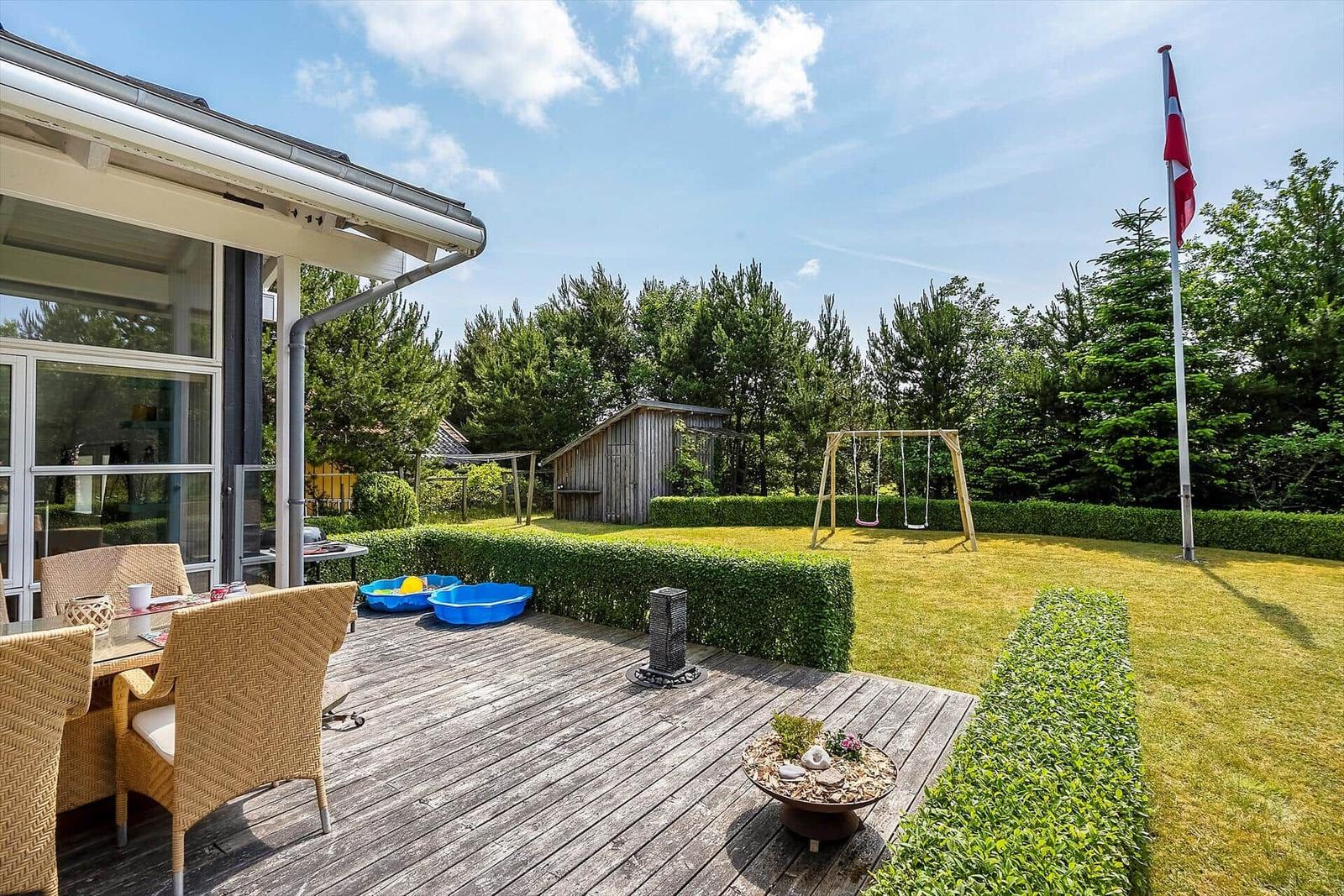 Terrasse mit Sitzgelegenheiten und Spielplatz im Garten.