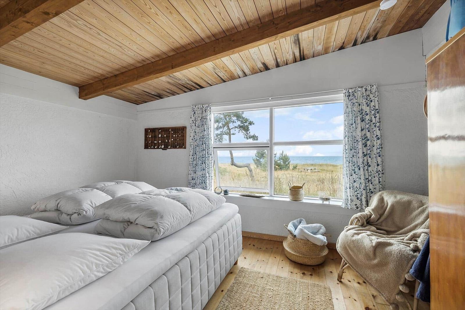 Bedroom with view of beach and sea through large window.