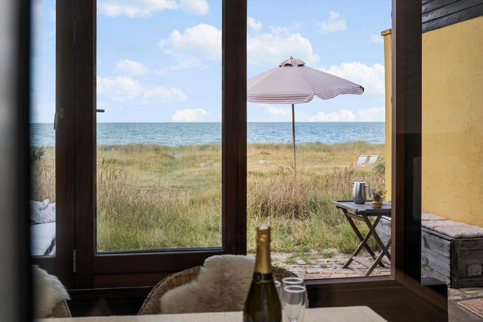 Through the window, you see a beach with sun lounger and umbrella.