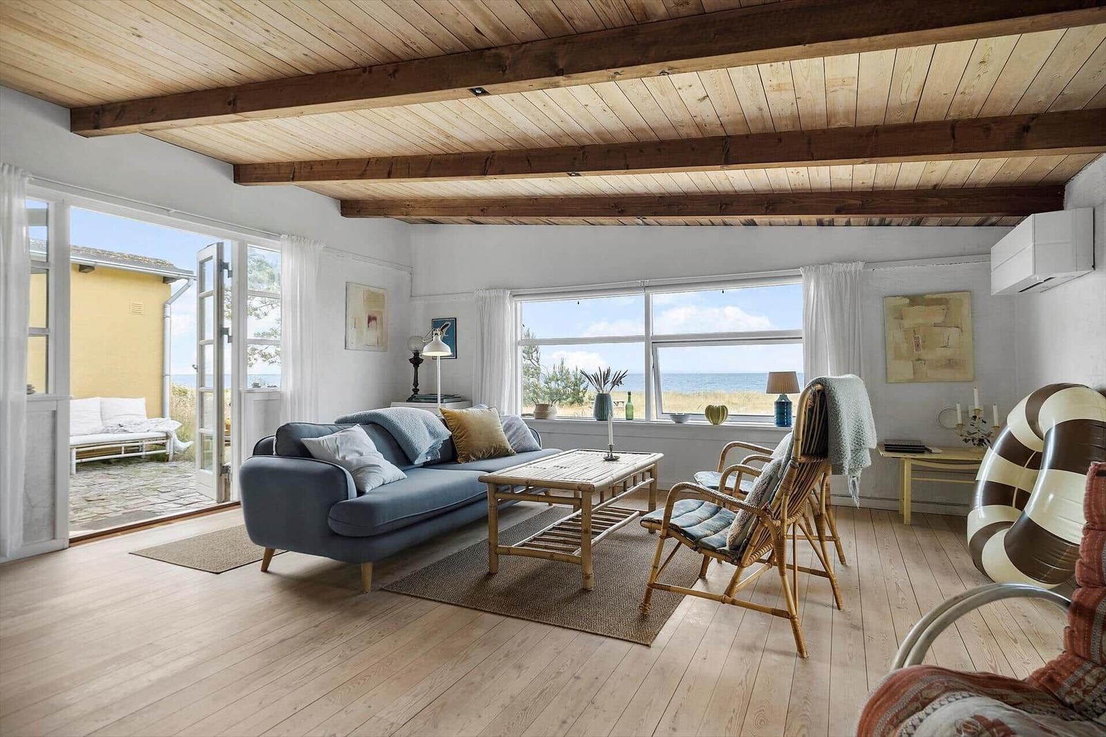 Living room with wooden ceiling, sofa, and sea view.