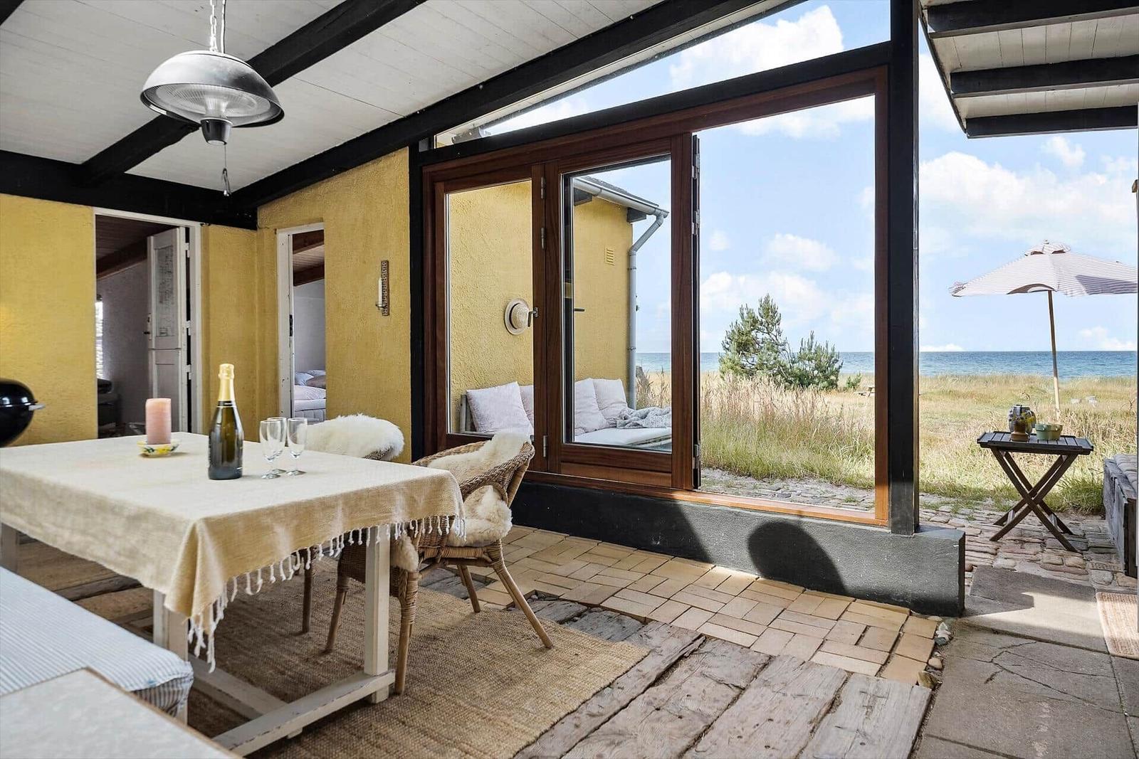 Terrace with table, chairs, and sea view. Large glass front with seating area.